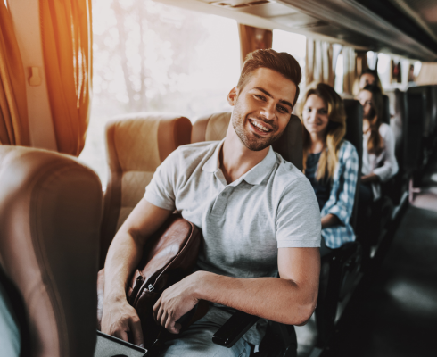 a man sits on a charter bus looking at the camera